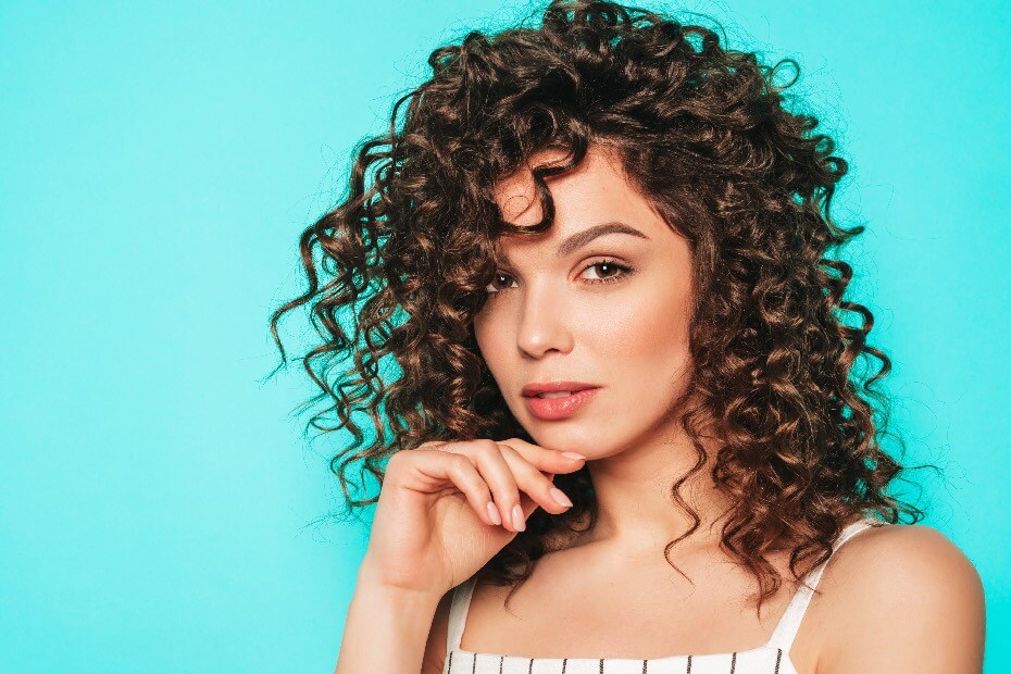 Mujer de frente con mirada fija y cabello rizado, sobre peinados para verte espectacular según tu tipo de cabello
