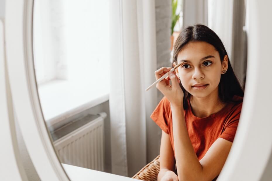 Mujer frente al espejo en una pausa en home office, manteniendo una rutina de belleza para el trabajo desde casa