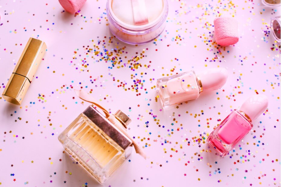 Artículos de belleza esparcidos como regalo en un fondo rosa