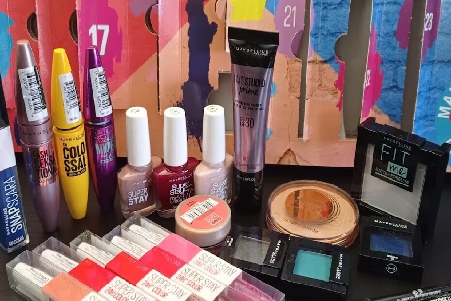 Artículos de maquillaje de Maybelline posando frente al calendario de adviento