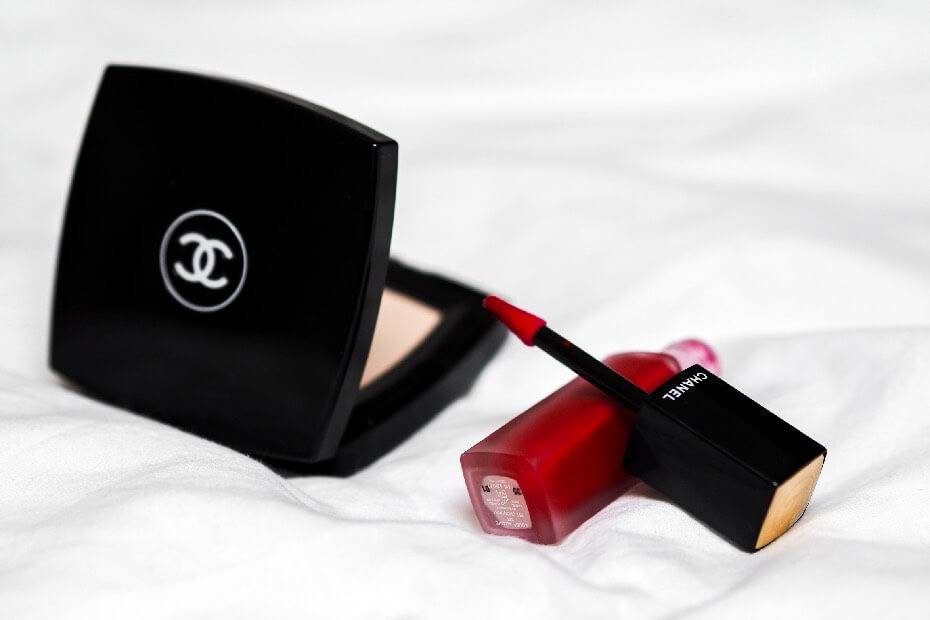 Polvo compacto con labial rojo de Chanel sobre cama blanca