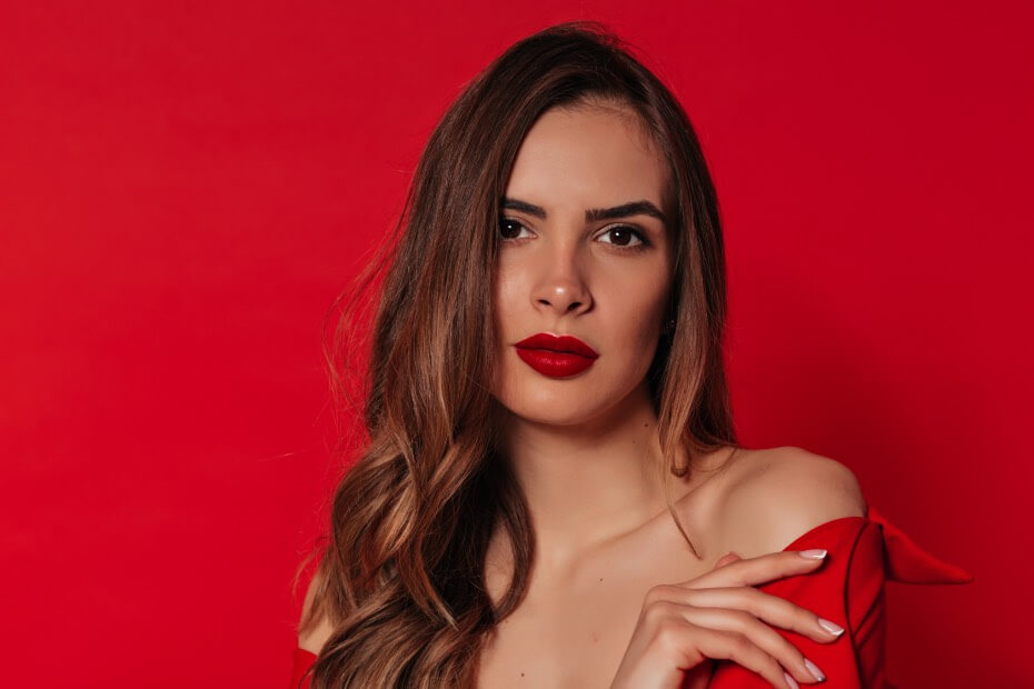 Mujer posando con labial rojo de Nara en fondo rojo como recomendación de Foriu