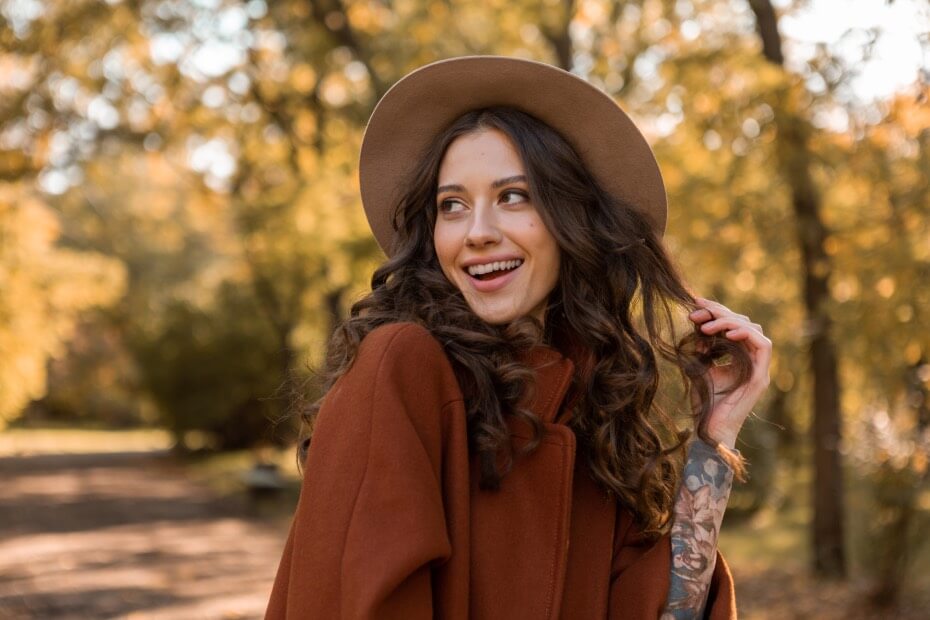 Mujer sonriendo con la piel y cabello ciuidados durante otoño