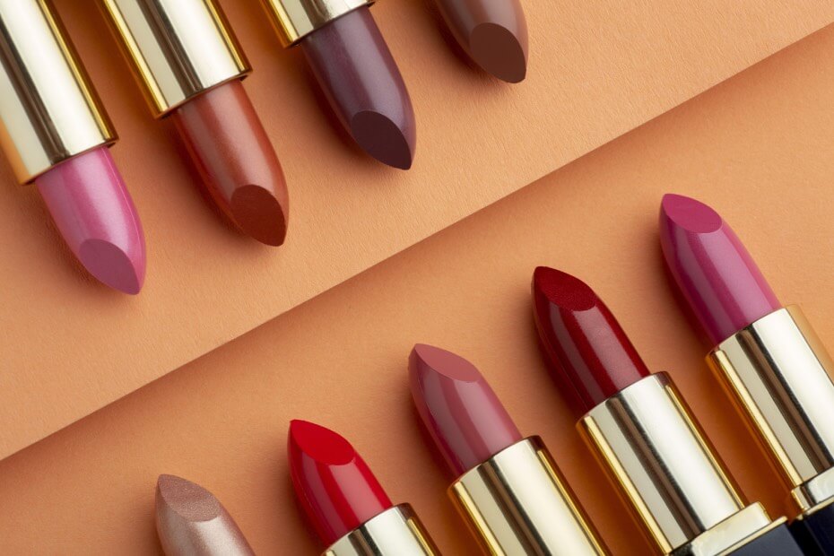 Labiales rojizos alineados sobre fondo naranja simulando batalla Mac y Chanel