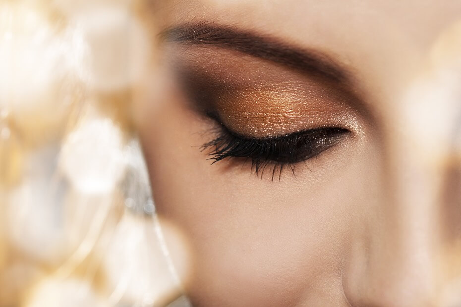 La mitad del rosto de una mujer, enfocado en un ojo cerrado, sobre tendencias de maquillaje que te harán brillar en tu graduación en 2023