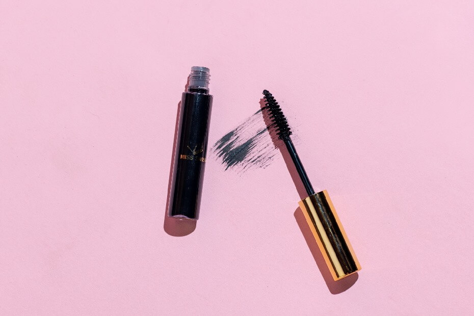 Máscara de pestañas abierto sobre mesa rosa, sobre productos de belleza que no pueden faltar en tu rutina diaria