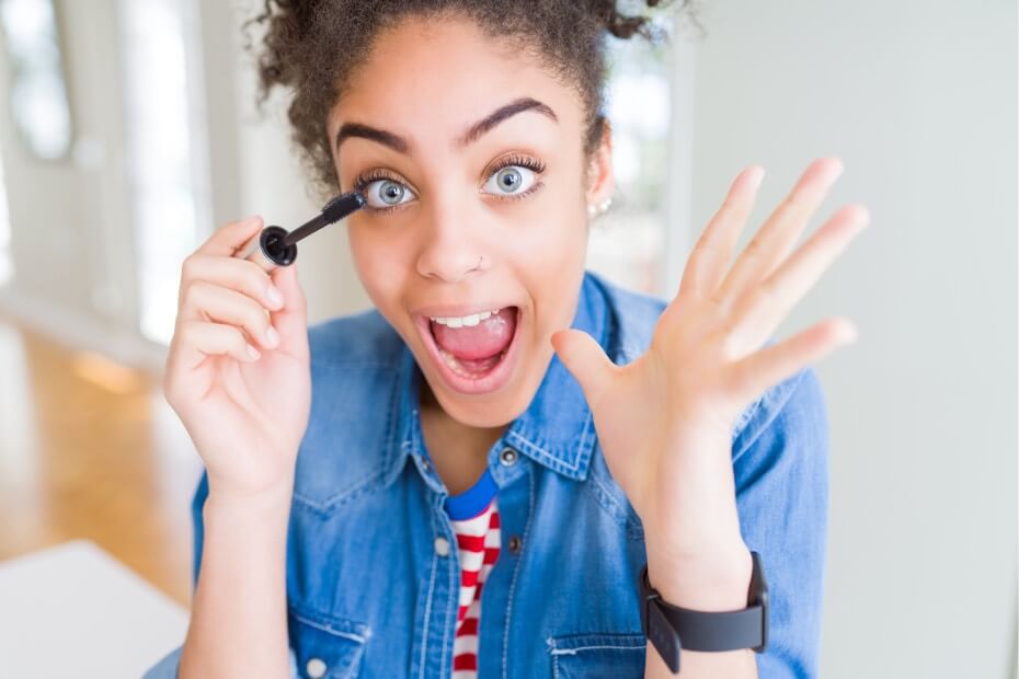 Mujer de frente con playera azul utilizando un rímel waterproof, sobre los 5 mejores rímeles waterproof para unas pestañas impresionantes
