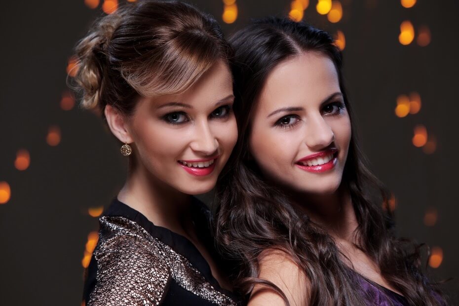 Dos amigas sonriendo peinadas y maquilladas, sobre descubre qué peinado va de acuerdo a tu signo zodiacal