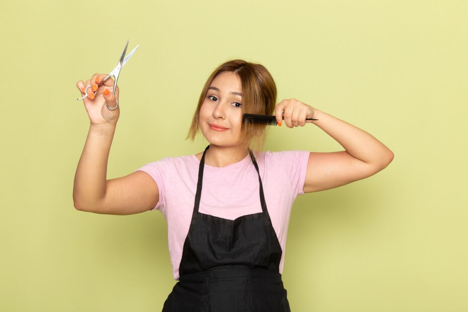 Mujer en fondo verde cortando las puntas de su cabello para mantenerlo sano